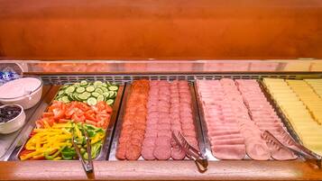 A buffet with various food items including sliced vegetables, meats, and dips.