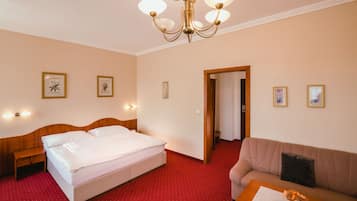 Una habitación de hotel con una cama, un sofá, una pequeña mesa con un jarrón y un candelabro.