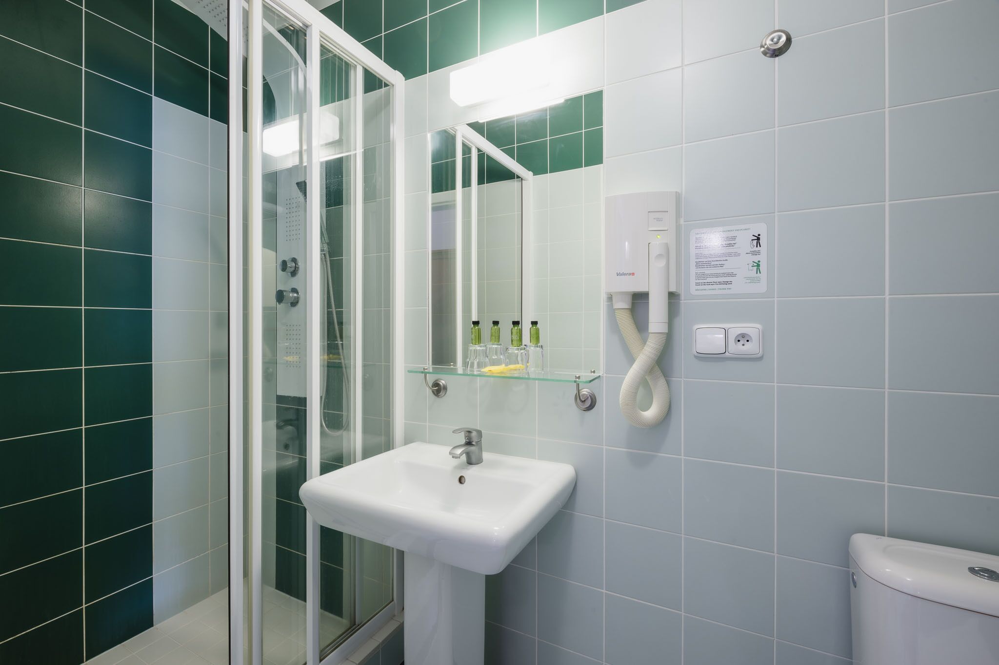 A bathroom with a glass shower enclosure, a white sink, and a mirror.
