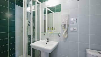 A bathroom with a glass shower enclosure, a white sink, and a mirror.