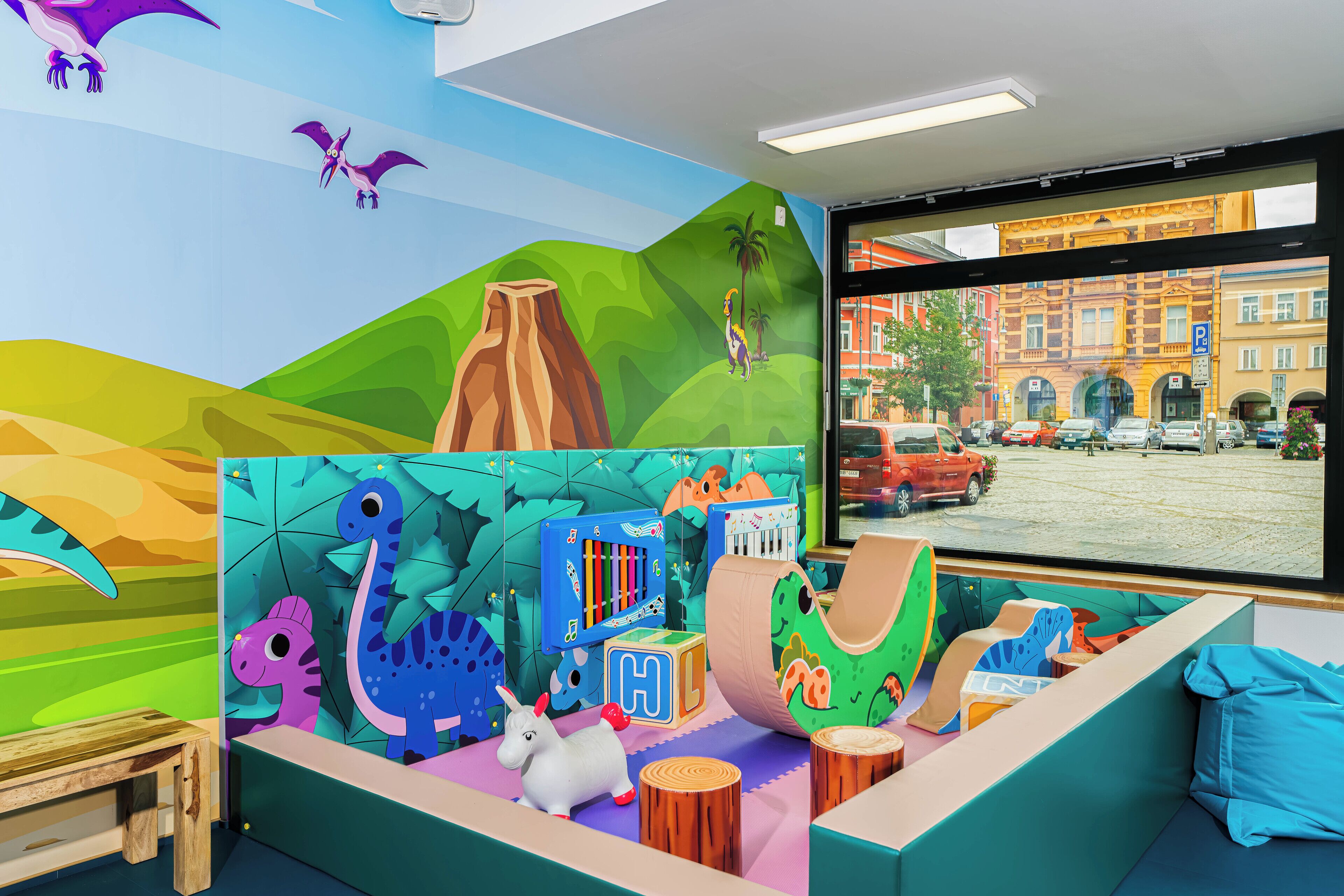 A colorful play area with dinosaur and animal decorations, a piano, and a window with a view of a city street.
