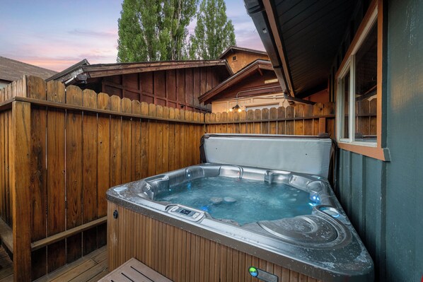 A hot tub with a wooden deck and a wooden fence.