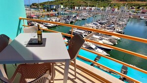 Een balkon met een tafel en stoelen met uitzicht op een jachthaven vol boten.