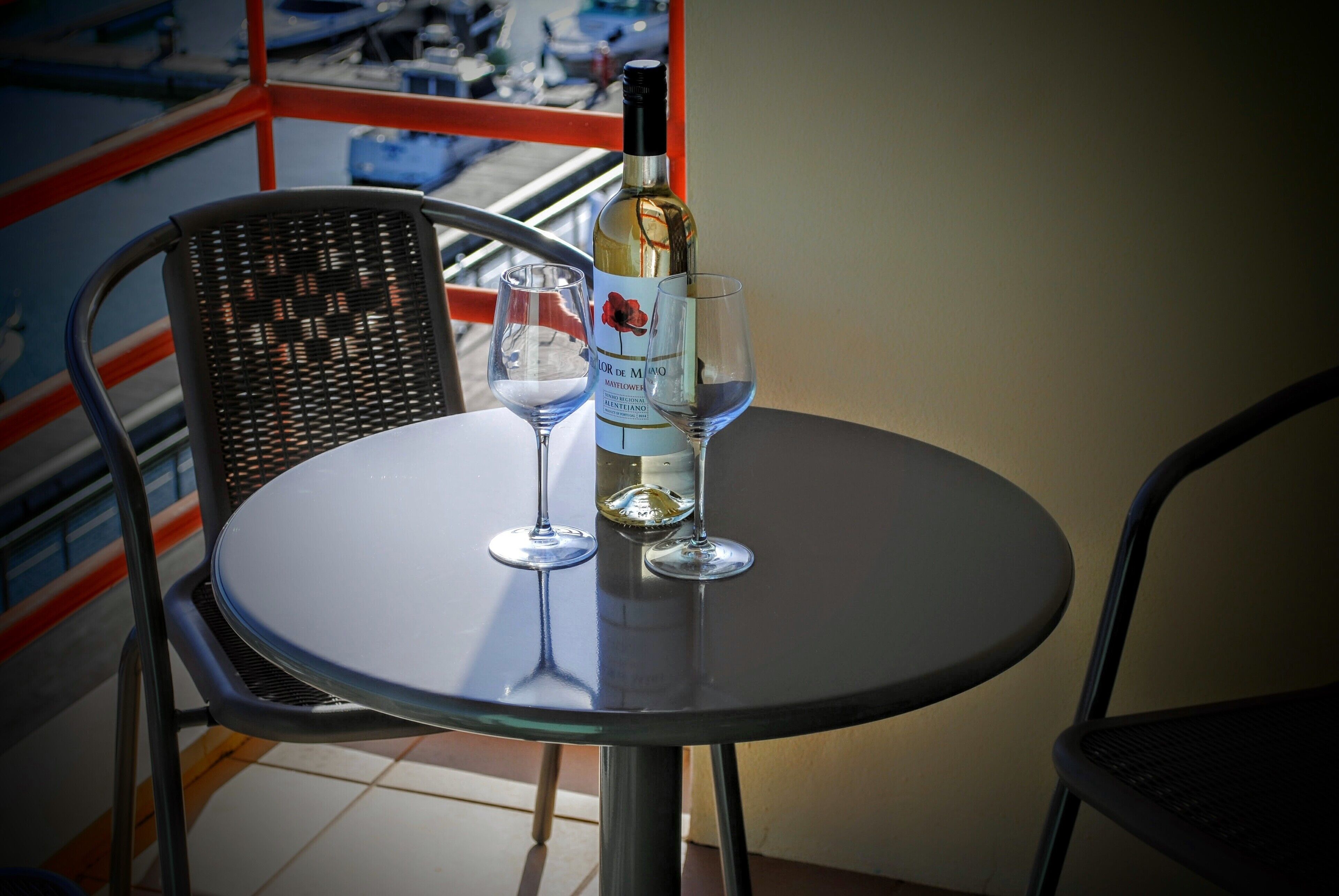 Uma mesa redonda com uma garrafa de vinho e duas taças de vinho.