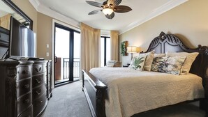 A hotel room with a bed, a dresser, a ceiling fan, and a view through the door. - 303W - Stay at the beach in this Elegant 2BR Condo! (Orange Beach)
