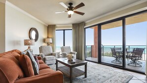 A hotel room with a sofa, armchairs, a coffee table, and a balcony with a view of the ocean. - 303W - Stay at the beach in this Elegant 2BR Condo! (Orange Beach)