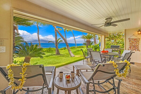 Eine Terrasse mit Blick auf den Ozean, Gartenmöbel und Deckenventilator.