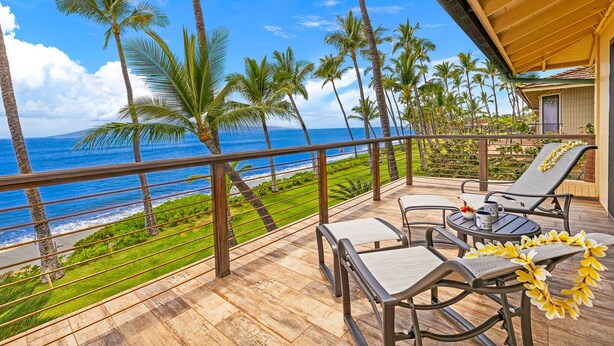 Une terrasse en bois, agréée de mobilier d’extérieur, qui offre une vue sur une plage et l’océan.