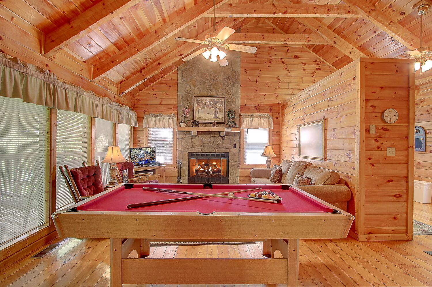 Un intérieur chaleureux de chalet en bois, avec une table de billard, une cheminée et un coin salon confortable.