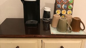 Una estación de café con una cafetera, vasos desechables y un soporte para tazas.