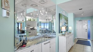 A kitchen with a marble countertop, white cabinets, and a large mirror. - SeaChase 503W RARE Reserved Covered Parking Included FREE (Orange Beach)