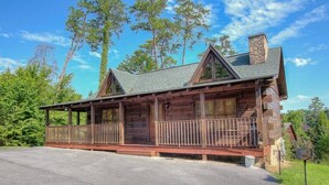 A log cabin with a porch, a chimney, and a stone foundation. - One of the coziest log cabins in the Smokies! With a hot tub and a jacuzzi tub! (Pigeon Forge)