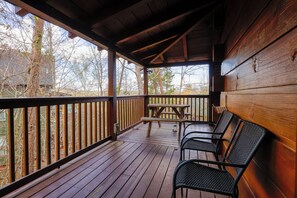 A wooden deck with a picnic table and chairs, surrounded by a wooden railing.