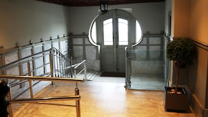 Una imponente escalera con piso de mármol y barandilla de hierro forjado.