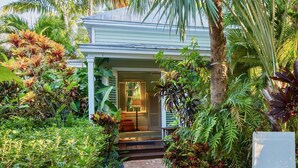 A house with a porch surrounded by lush tropical plants. - **THE ROYAL COMPOUND @ THE ANNEX** Pool + Last Key White Glove Service... (Key West)