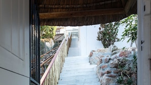 A staircase leading up to a building entrance, with a metal railing on one side and a stone wall on the other.