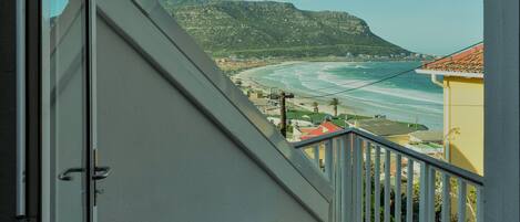 A balcony with a view of a beach and mountains.