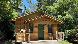 A wooden cabin with a green door, a sign reading 'LOT-13,' and a small porch with a table and chairs. - Cozy 1BR with log cabin near Pigeon Forge Parkway (Pigeon Forge)