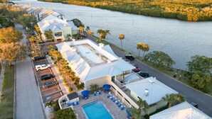 A resort with a swimming pool, lounge chairs, and a view of a river.