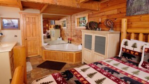 A wooden cabin interior with a wooden bed, a bathroom with a bathtub, and a wooden wardrobe. - Cutest, comfiest log cabin with great screened in porch! (Sevierville)