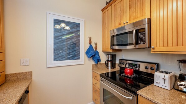 A kitchen with wooden cabinets, a microwave, a stove, a toaster, and a coffee maker.