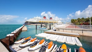 A cruise ship docked at a port with a jet bridge and a jetty with water taxis.