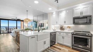 A modern kitchen with white cabinetry, a built-in oven, and a large island. - Seachase 303E: Gulf Views & Premium Amenities (Orange Beach)