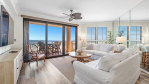 A spacious living room with a large sliding glass door leading to a balcony, a ceiling fan, and a white sofa. - Seachase 303E: Gulf Views & Premium Amenities (Orange Beach)