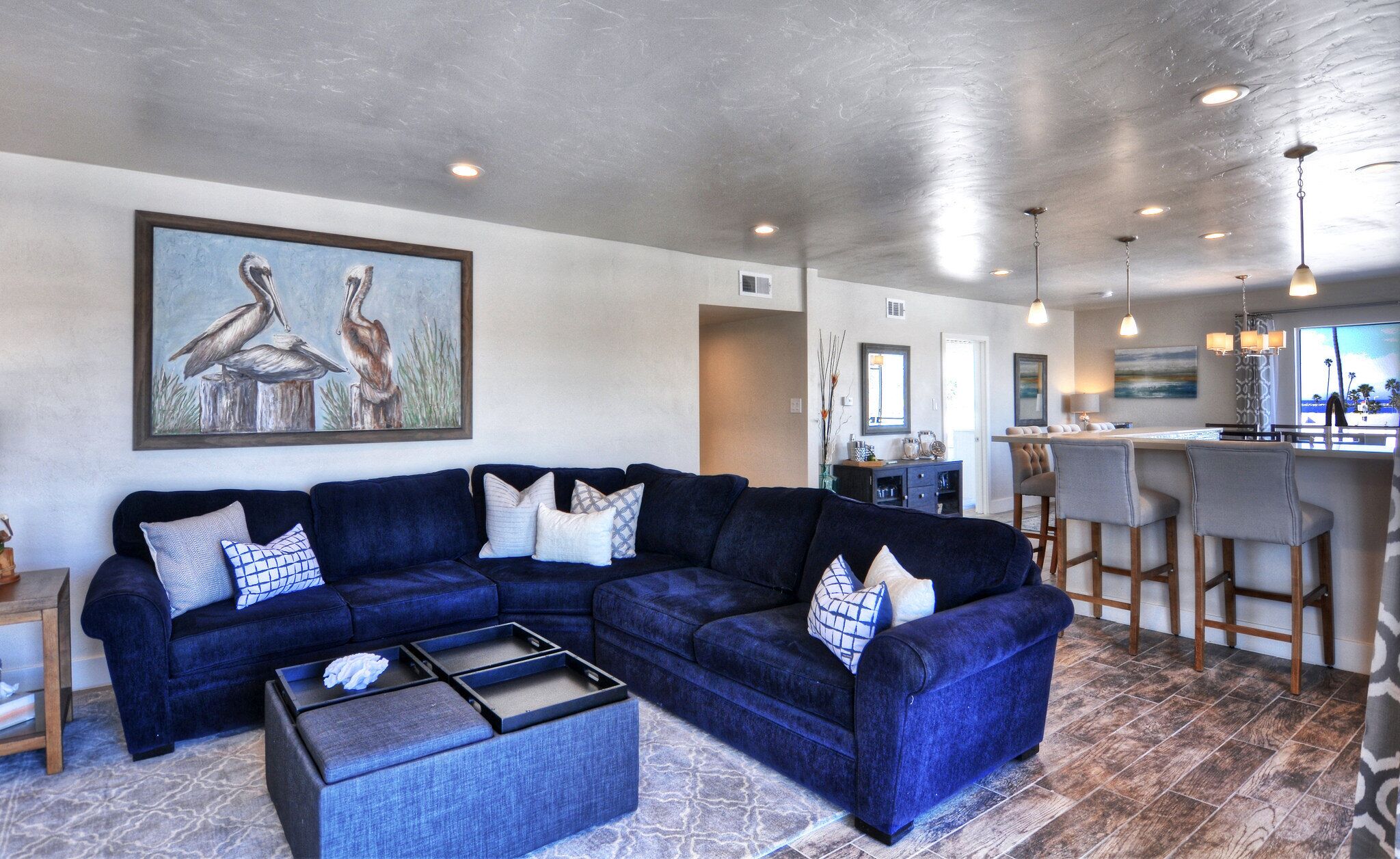 A modern living room with a sectional sofa, a coffee table, and a painting on the wall.