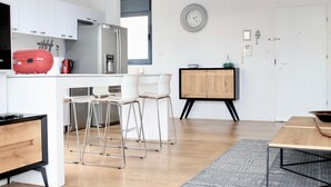 Eine moderne Küche mit weißen Schränken, einem roten Gerät und einem Esstisch aus Holz mit Barhocker.