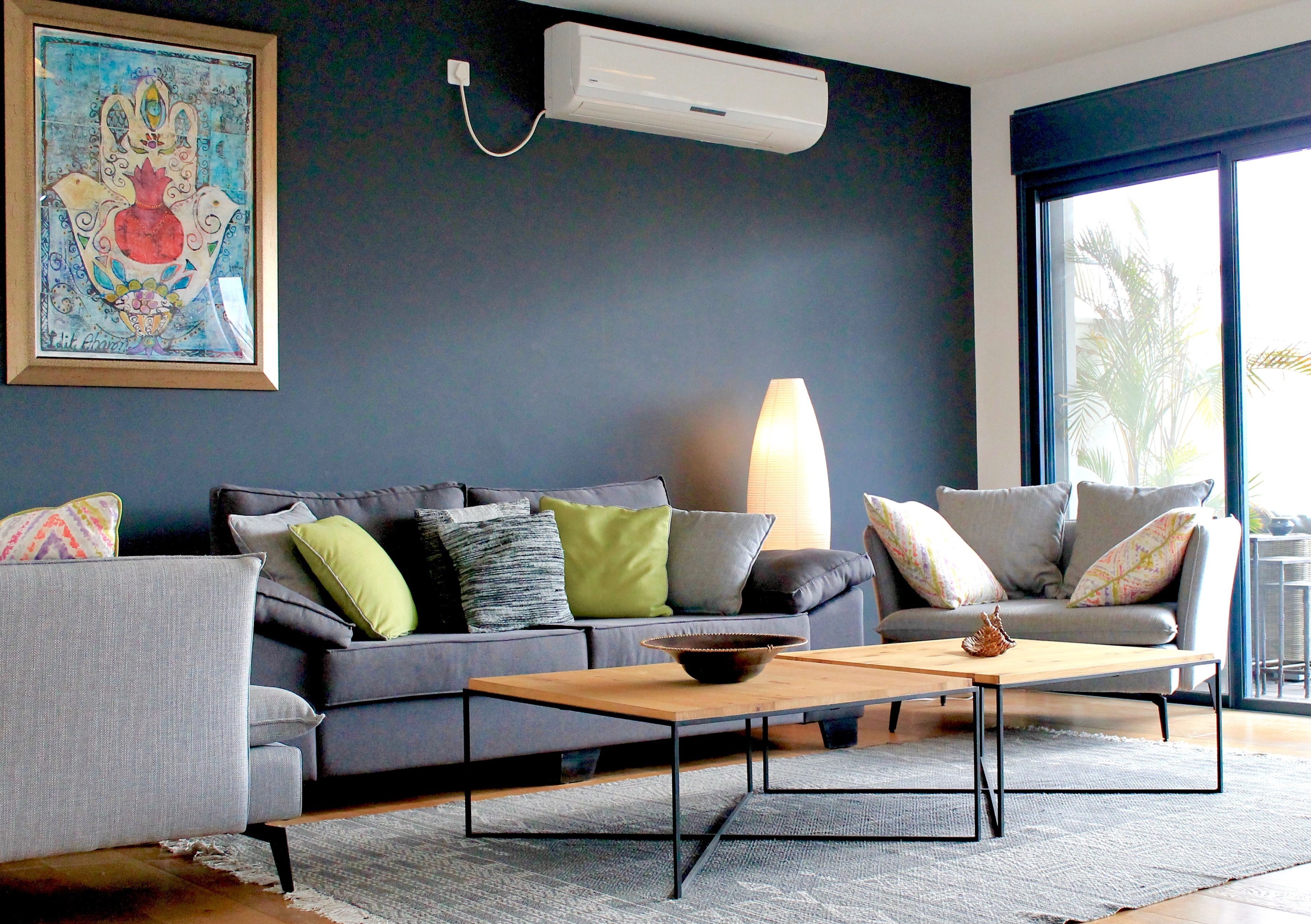 Un salon moderne avec un canapé gris, une table basse en bois et une grande fenêtre laissant entrer la lumière naturelle.