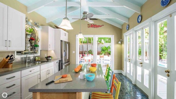 Una cocina amplia con armarios blancos, una isla central y vistas a un patio.