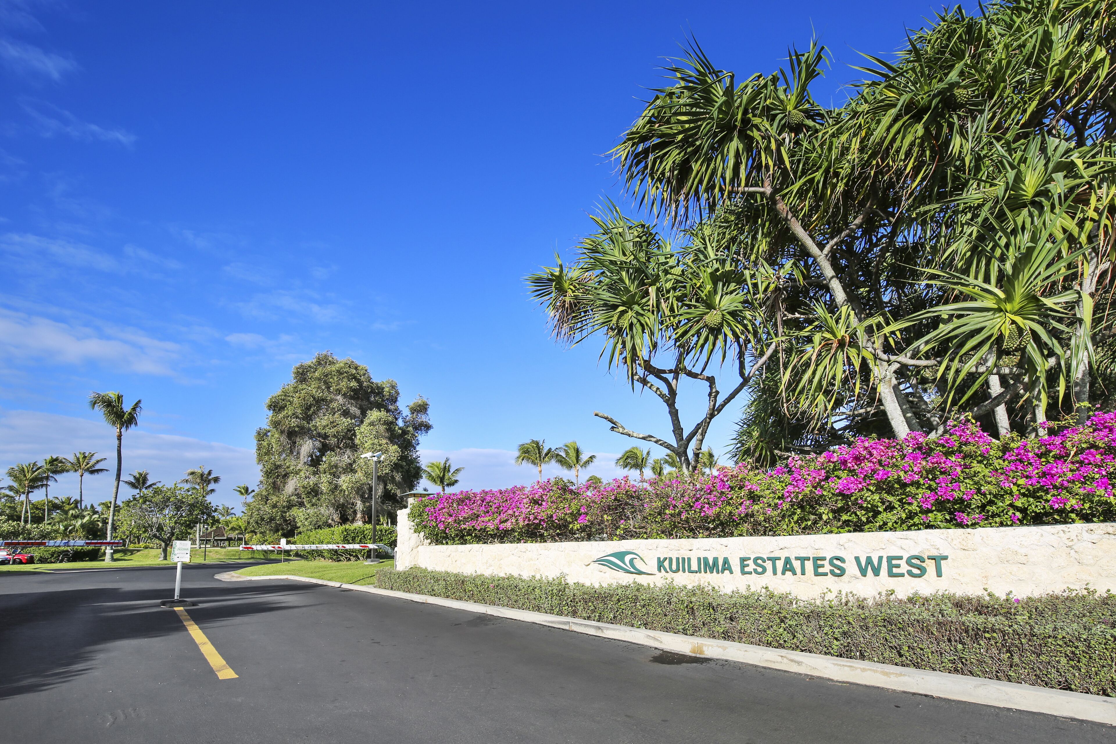 A road leading to a gated entrance with a sign for 'Kuilima Estates West'.