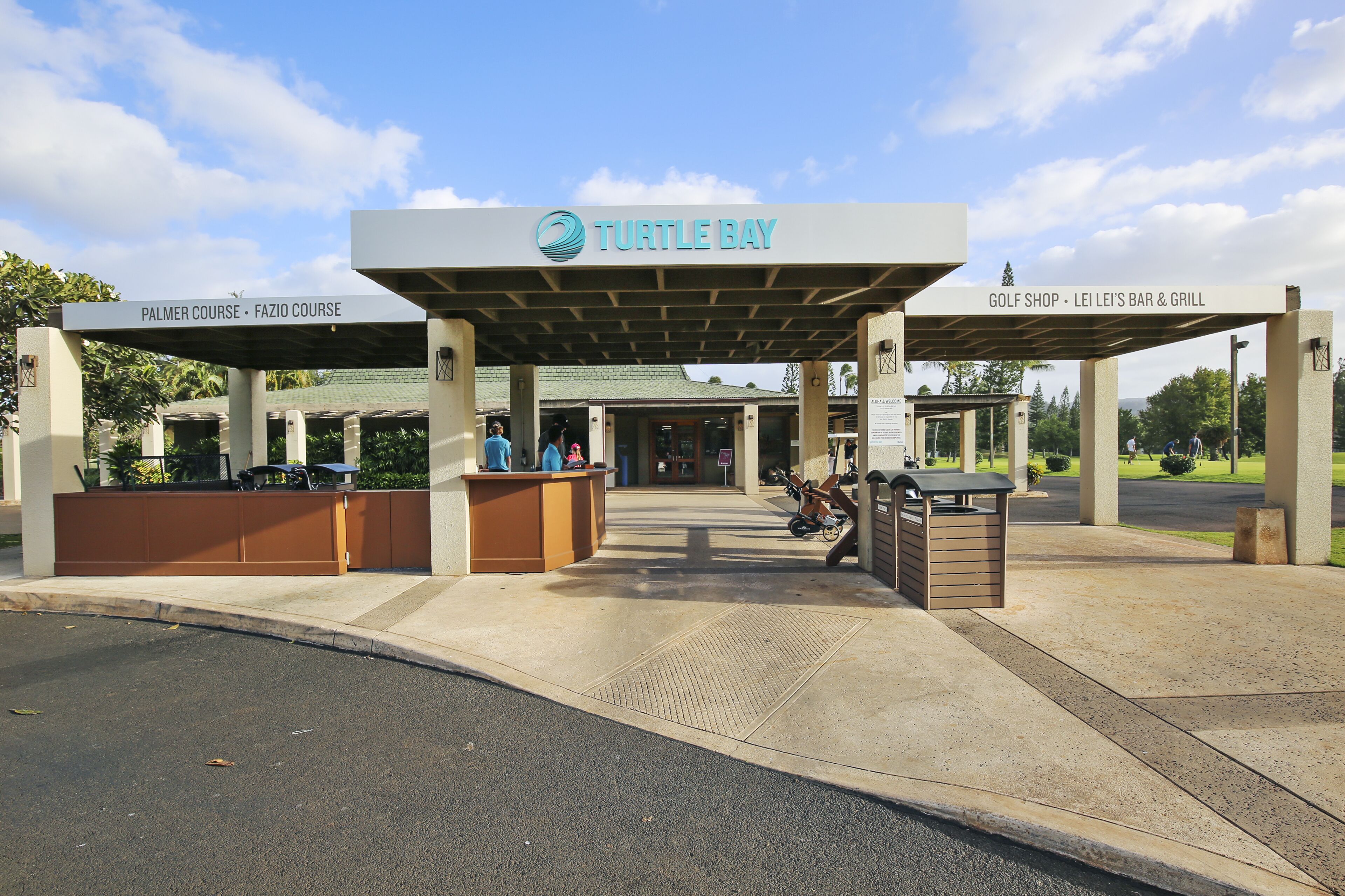 Una entrada techada a Turtle Bay con indicaciones para el Palmer Course, el FaZio Course, y una tienda de golf, bar y parrilla.