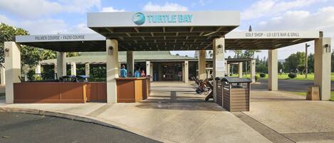 A covered entrance to Turtle Bay with signs for Palmer Course, FaZio Course, and a golf shop, bar, and grill.