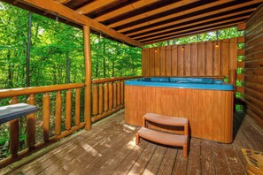 Une terrasse en bois avec un jacuzzi, des rampes en bois et un banc.