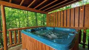 Un bain à remous sur une terrasse en bois, entouré d’arbres.