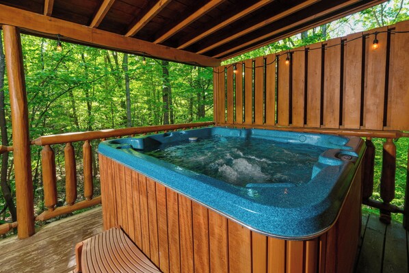 Un bain à remous sur une terrasse en bois, entouré d’arbres.