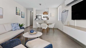 A modern living room with a sofa, a coffee table, and a dining area with chairs and a table.