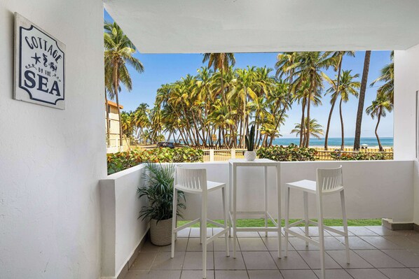 A terrace with white chairs and a sign reading "COTTAGE BY THE SEA".