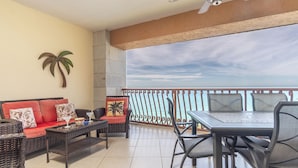 A balcony with a view of the sea, furnished with a sofa, chairs, and a table. - Sonoran Sun E-708 Sunset Serenity Relaxing Oceanfront Condo (Puerto Penasco)