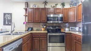 A kitchen with wooden cabinets, stainless steel appliances, and a granite countertop. - Sonoran Sun E-708 Sunset Serenity Relaxing Oceanfront Condo (Puerto Penasco)