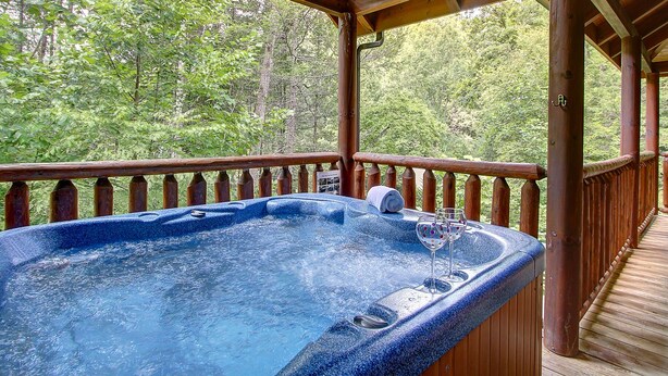 Un bain à remous sur une terrasse en bois, avec vue sur une forêt.
