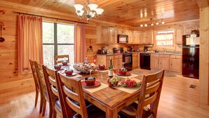 Une cabane en bois dotée d’un coin repas avec une table dressée pour quatre personnes, entourée de chaises en bois.