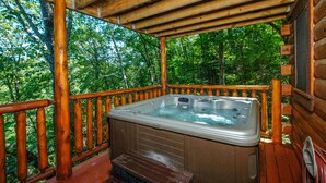 Une terrasse en bois avec un jacuzzi, entourée d’arbres.