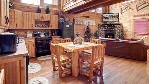 Un intérieur de chalet chaleureux comprenant un coin repas, une cuisine et une cheminée.