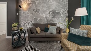 A modern living room with a grey patterned wall, a brown sofa, and a patterned armchair. - Charme 308 (Rome)