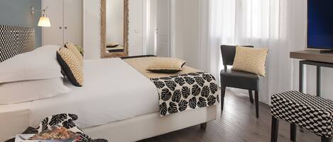 A hotel room with a bed, a chair, a desk, and a television.
