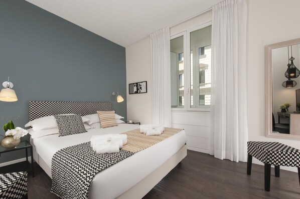 A modern bedroom with a large bed, bedside tables, a chair, and a mirror. - Charme 308 (Rome)