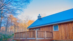 Une cabane en bois avec un toit bleu, une terrasse et une cheminée.